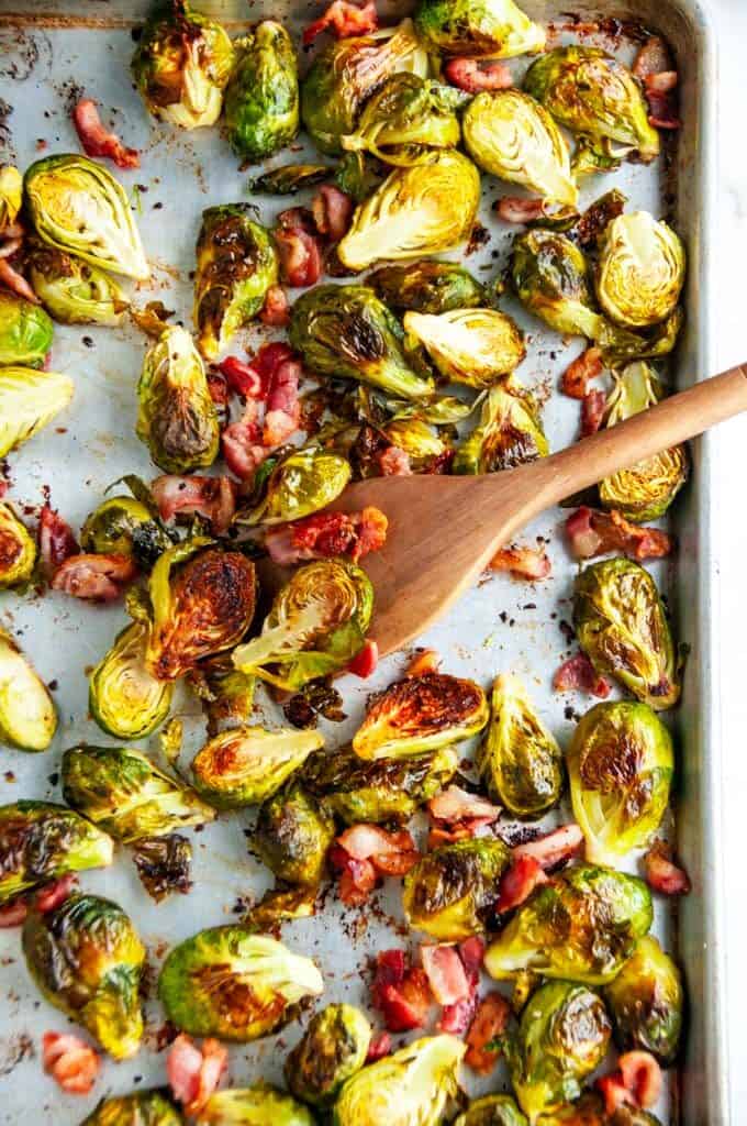 Sheet Pan Bacon Garlic Brussels Sprouts on a sheet pan with wooden spoon