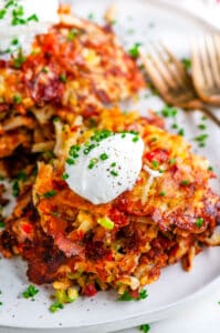 Cheesy Egg and Ham Hash Browns on white plate with gold forks