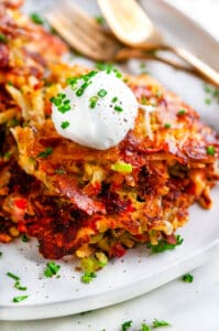 Cheesy Egg and Ham Hash Browns on white plate with gold forks