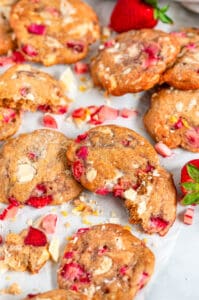 White Chocolate Strawberry Rhubarb Cookies on white parchment and marble with lemon zest close up