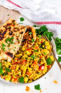 Indian Egg Scramble Breakfast with naan bread and gold fork on gray plate and wood white marble side view