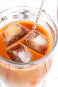 Iced Lavender Vanilla Latte in glass mug with silver stirring spoon close up side view