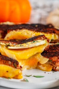 Pumpkin Grilled Cheese Sandwich on gray plate with apple slice and sage on white marble