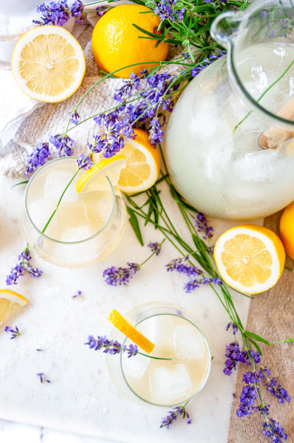 Boozy Lavender Lemonade Cocktail over ice in a wine glass with lavender sprig and lemon garnish