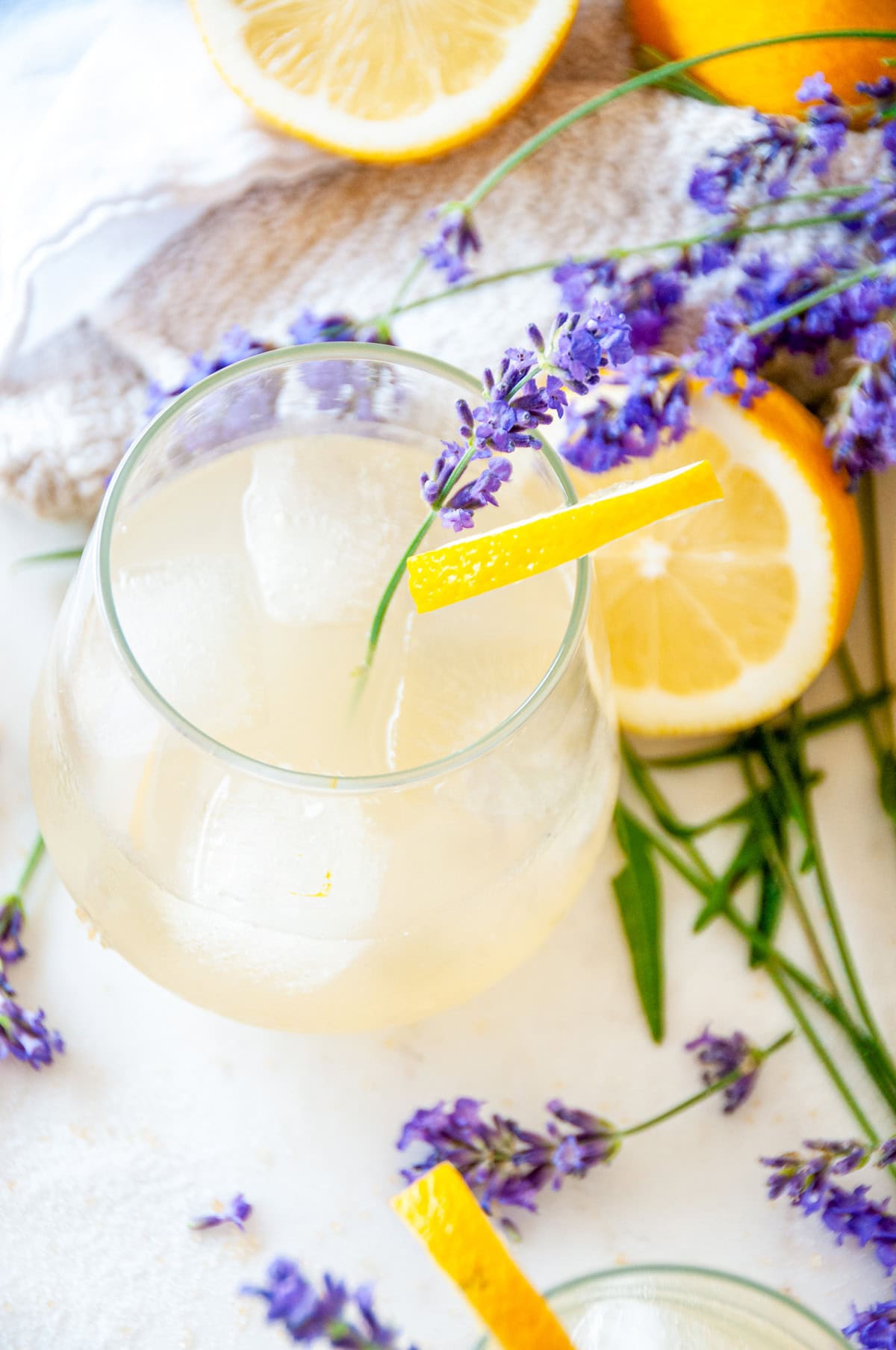 Boozy Lavender Lemonade Cocktail over ice in a wine glass with lavender sprig and lemon garnish